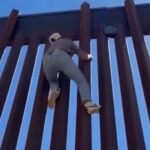Man climbs US-Mexico border wall to demonstrate the level of difficulty it requires.