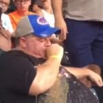 Man pukes on self at sports event (in a stadium), appears to try to be discreet…