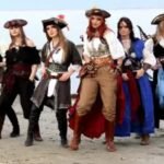 Porpoise scares two kids, and female pirates dance on a beach.