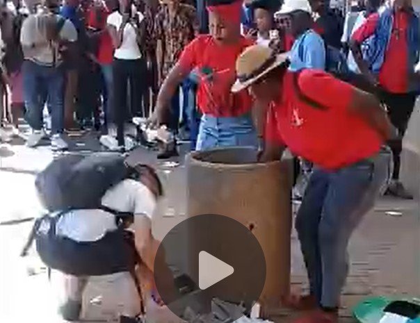 Migrants demonstrate their culture by removing trash from rubbish bin each time a man tries to clean the ground nearby/dispose of waste.